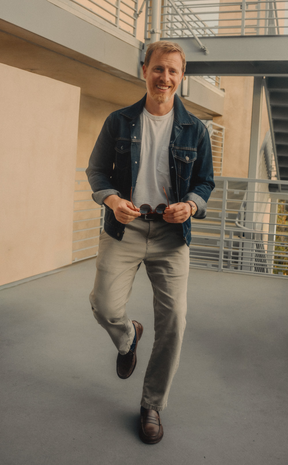 Andrew wearing a denim jacket tucked into a white t-shirt, khaki pants, and brown loafers.