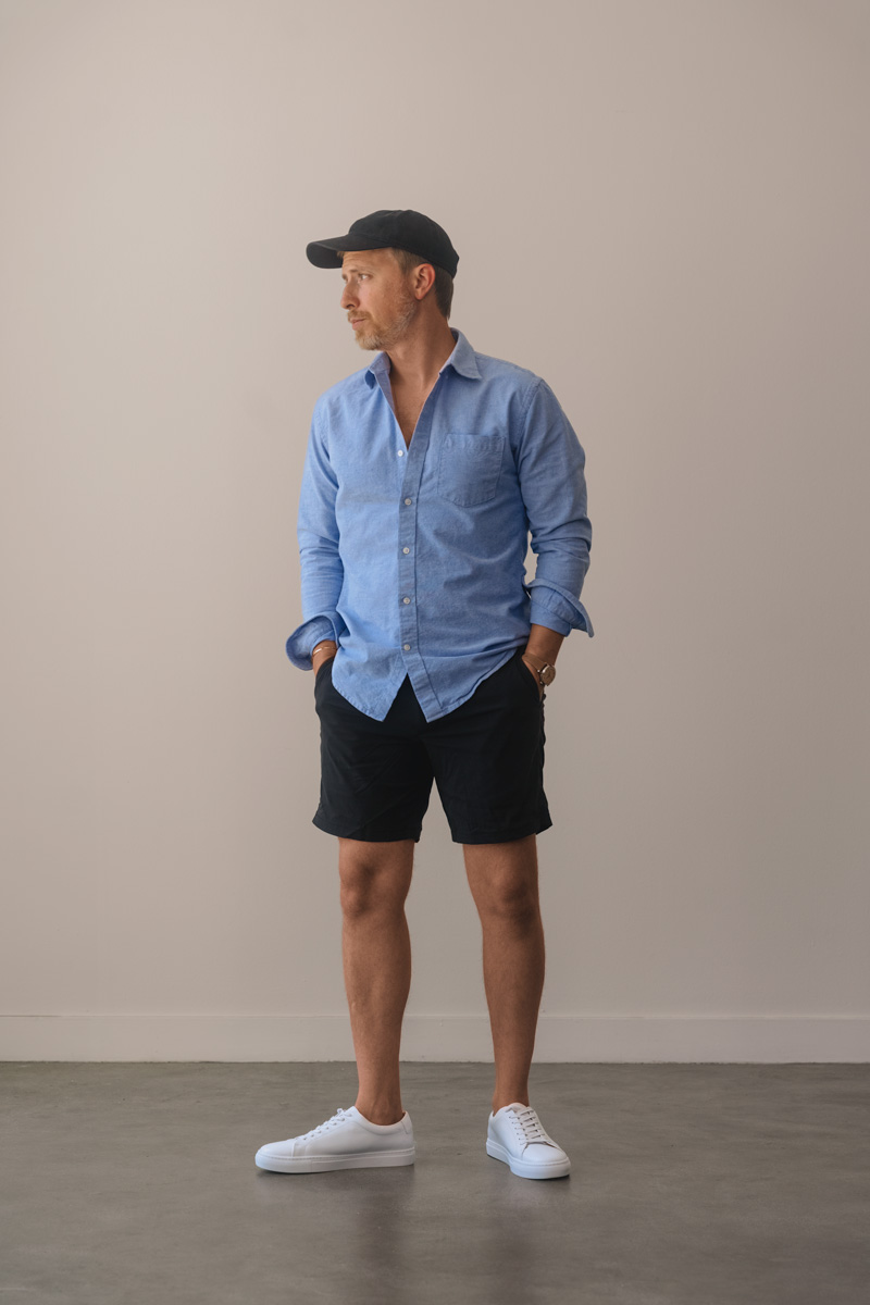 blue oxford shirt with black shorts and white sneakers mens outfit