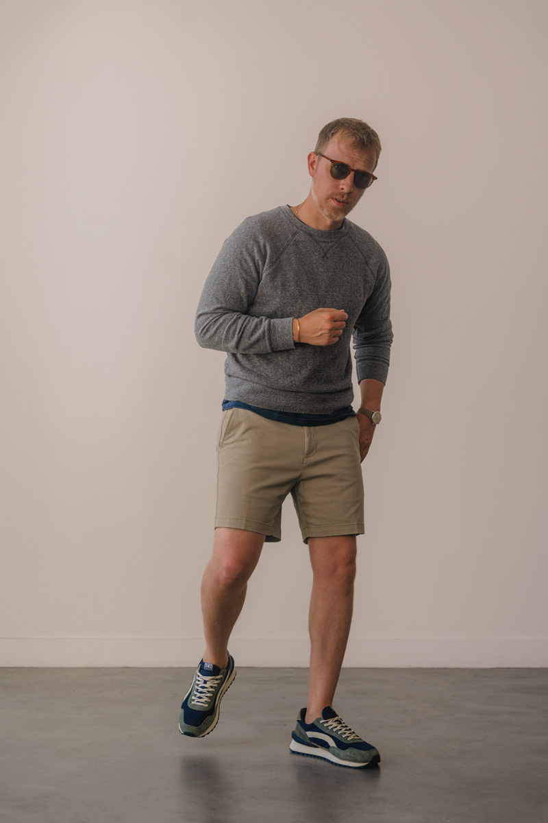 man wearing green running sneakers with gray sweatshirt and tan shorts outfit