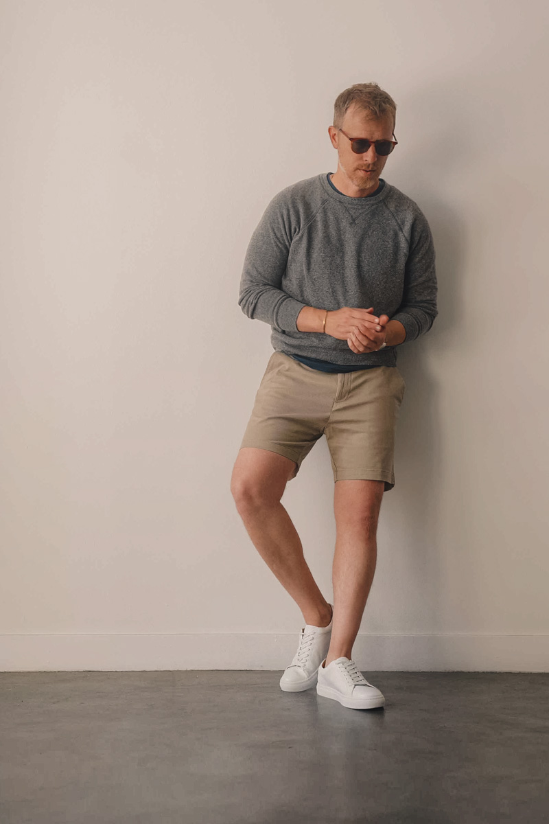 timeless mens summer outfit with gray sweatshirt, khaki shorts, and white sneakers