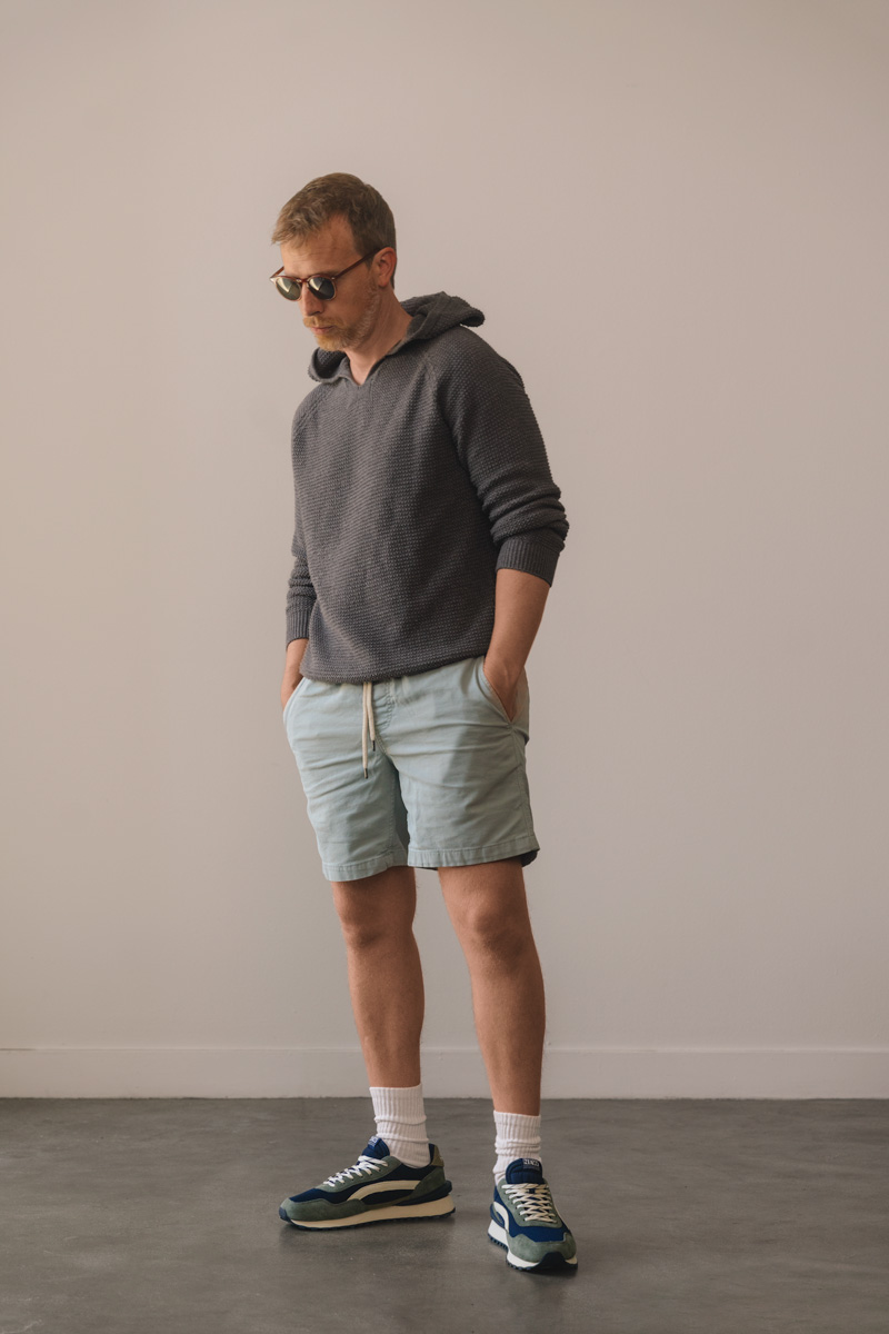 knit hoodie with teal shorts, crew socks, and green running shoes